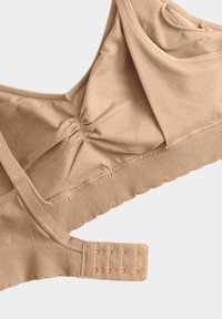 Sujetador inalámbrico de tela suave en color beige con cierre ajustable de gancho y ojal y detalle fruncido en el centro de cada copa.