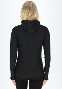 Black long-sleeve athletic hoodie with a textured fabric, fitted design, and a hood; features thumbholes in the sleeves and a subtle sheen.