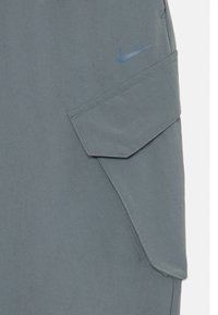 Γκρίζες cargo βερμούδες με τσέπη καπάκι, αναπνέον ύφασμα και μικρό μπλε λογότυπο Nike. Λείο τελείωμα με ραφές.