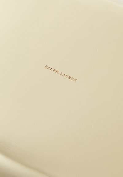 Béžový keramický tanier s hladkým povrchom a jemným leskom. Obsahuje vytlačené logo "RALPH LAUREN" v zlate. Okrúhly tvar, minimalisický dizajn.
