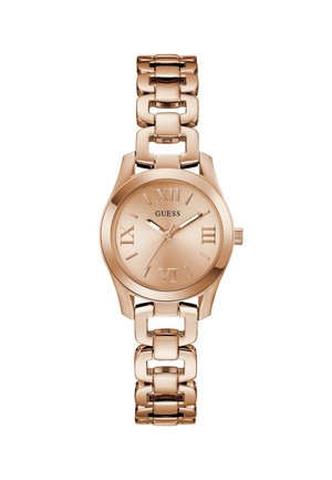 Montre-bracelet en métal or rose avec bracelet à maillons, cadran rond, chiffres romains et logo "GUESS" au centre, affichant l'heure 1:10:34.