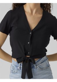 Top court noir avec encolure en V, manches courtes et fermeture à boutons. Dispose d'un détail noué à l'avant et d'une texture de tissu lisse.