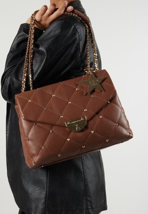 Bolso de mano de cuero acolchado marrón con una correa de cadena dorada, un charm en forma de estrella, acentos de tachuelas y un cierre de pestaña magnética.
