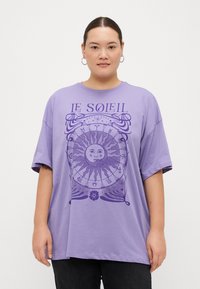 Camiseta oversized de color lavanda hecha de algodón, con un gráfico de sol y el texto "LE SOLEIL" en púrpura oscuro. Mangas cortas, corte relajado.