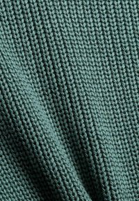 Teksturowana dzianina w stonowanym odcieniu teal, z regularnym wzorem splecionych włókien, tworzącym miękką, elastyczną powierzchnię.