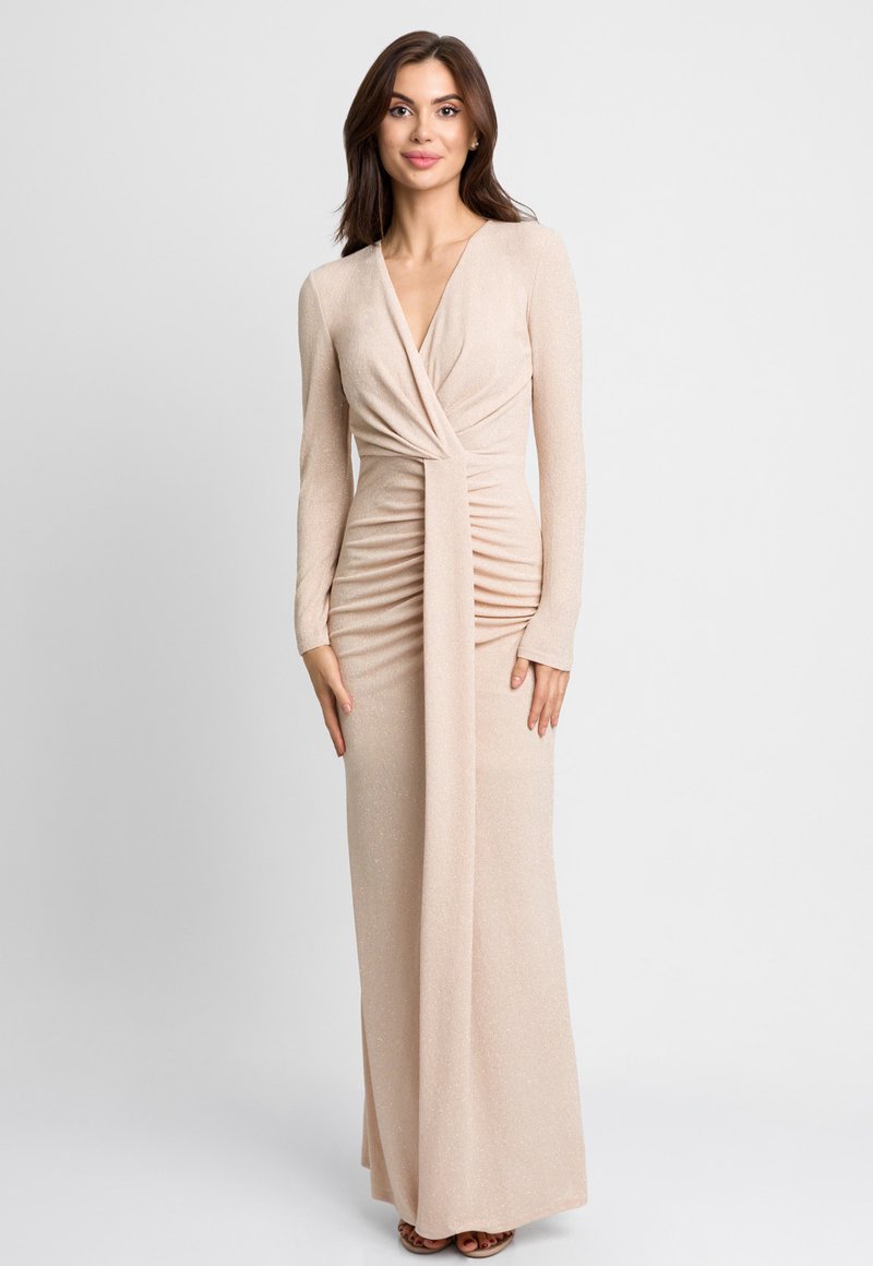Długa, dopasowana sukienka z połyskującego beżowego materiału. Charakteryzuje się głębokim dekoltem w kształcie litery V, długimi rękawami i marszczeniami w talii. Gładka struktura.