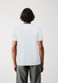 White cotton t-shirt with short sleeves and a round neck, featuring a smooth texture and a simple, unembellished design.