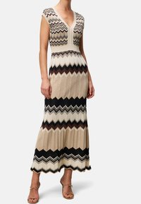 Długa sukienka bez rękawów z wzorem jodełki w odcieniach beżu, brązu i czerni, z dekoltem w kształcie litery V i dopasowanym gorsetem.
