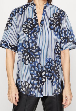 Blouse à manches courtes en bleu clair avec des motifs floraux bleu foncé et des rayures verticales. Dotée d'un col en V et d'un tissu doux et léger.