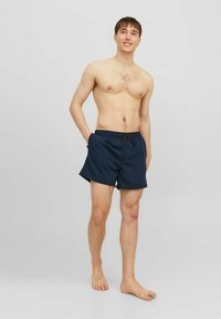 Shorts da bagno blu navy con vita elastica e coulisse. Il design presenta uno stile semplice e privo di decorazioni, con lunghezza sopra il ginocchio.