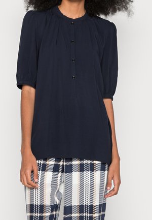 Marineblaue Bluse mit kurzen Ärmeln, runder Ausschnitt, Knopfverschluss auf der Vorderseite und puffigen Ärmeln. Der Stoff scheint leicht und glatt zu sein.