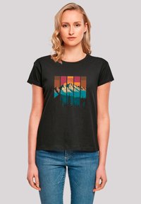 Black cotton t-shirt featuring a graphic print of mountains and trees in teal, orange, and pink against a striped background. Short sleeves.