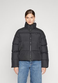 Giacca a vento nera con colletto alto, chiusura con zip e due tasche laterali. Presenta un design trapuntato e un'adeguata isolamento.