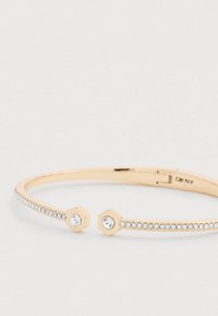 Aranyszínű karperec két hatszögletű díszítéssel, áttetsző kristályokkal, valamint a szalag szélén kisebb kristályok sorával.