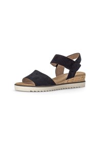 Las sandalias de cuña de gamuza negra presentan una amplia correa sobre los dedos y dos correas entrelazadas en el tobillo, con un tacón de corcho texturizado y una suela de goma.