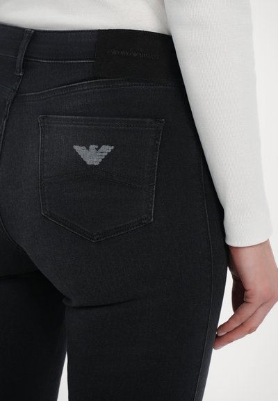 Mörk denimjeans med en figurnära design, som har en bakficka med logotyp i grått. Midjebandet har en svart tygetikett med varumärkesnamnet.