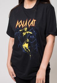 Black cotton T-shirt featuring a graphic print of a figure in yellow, with "DOJA CAT" text in bold red and blue lightning accents.