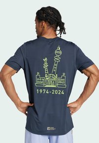Navy blue athletic t-shirt with short sleeves and a graphic design in neon yellow, featuring landmarks and the text "1974-2024" on the back.