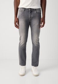 Jeans din denim gri cu o ușoară decolorare, design cu cinci buzunare și croială dreaptă, asortați cu adidași albi.