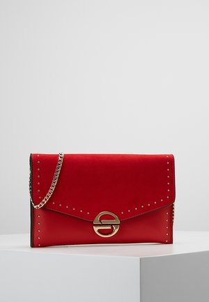 Pochette rectangulaire rouge avec des clous dorés le long des bords, un fermoir circulaire doré et une bandoulière chaîne dorée, présentée sur un socle blanc.