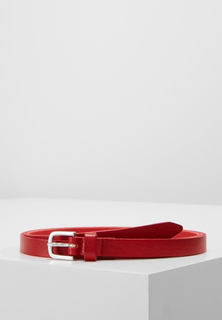 Ceinture en cuir rouge avec boucle rectangulaire argentée, enroulée sur une surface blanche sur fond uni.
