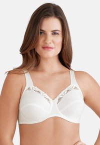 Lichtcrème beha met kantafwerking, beugel, brede verstelbare bandjes en een subtiel textuurpatroon. Heeft een strikdetail in het midden.