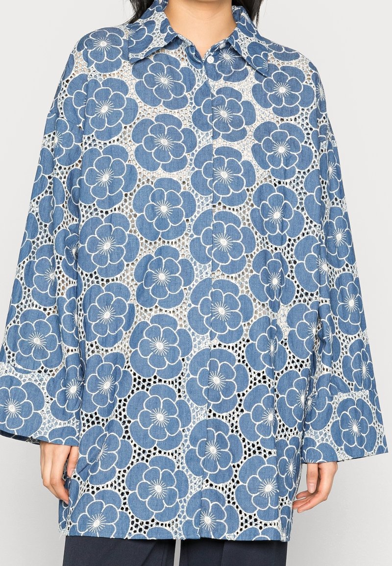 Camisa de estampado floral azul con un corte relajado, que presenta un cierre de botones en el frente, un gran cuello y mangas de campana, confeccionada con tejido estampado.