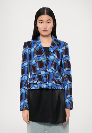 Blue and black patterned blazer with a notched collar, two front pockets, and button closure. Worn over a black top and denim skirt.