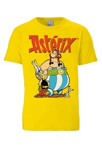 Yellow cotton t-shirt featuring a printed graphic of two cartoon characters with a dog, along with the text “Astérix” in bold red letters.