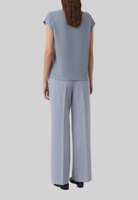 Lichtblauw ribbed top met cap sleeves, gecombineerd met lichtblauwe wijde broek. Glad stof, minimalistisch ontwerp en ontspannen pasvorm.