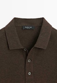Brązowa koszulka polo z fakturowanej tkaniny, z płaskim kołnierzykiem, trzema guzikami i metką z napisem "Massimo Dutti".