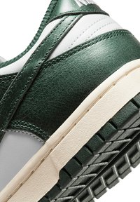 Sneaker verde e bianco con tomaia in pelle testurizzata, cuciture in evidenza e suola in gomma con un design del battistrada a motivo.
