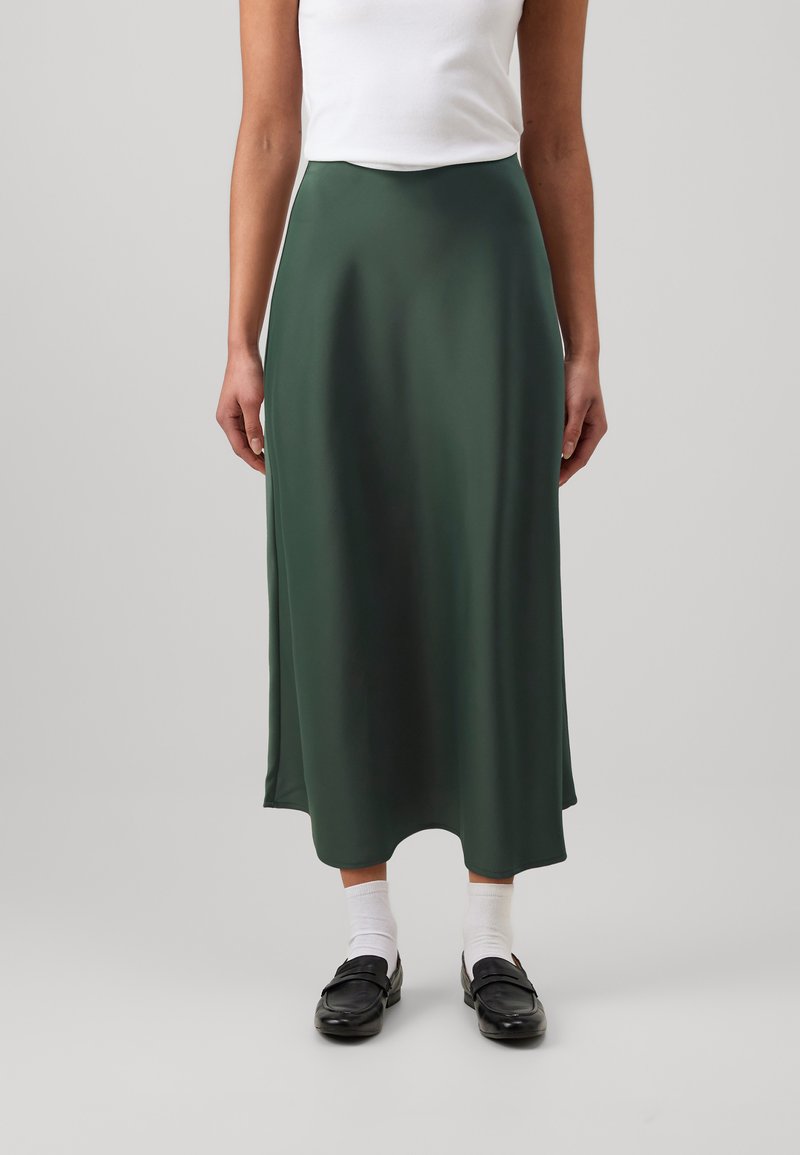 Fustă midi din satin verde, cu o textură netedă, formă fluidă și talie elastică, asortată cu mocasini negri și șosete albe.