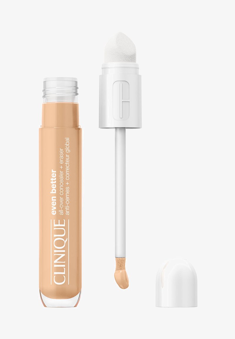 Concealer-rør med en beige væskeformel og en hvid applikator. Låget er rundt og hvidt; røret har mærkenavnet og produktinformation.