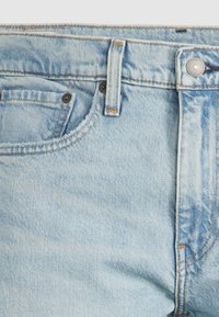 Ljusblå denimjeans med en klassisk femficksdesign, blekt utseende och synliga sömnadsdetaljer. Metallknäppning i midjan.