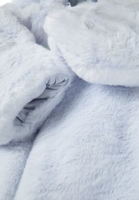 Hellgraues Kunstfellgewebe mit einer weichen, plüschigen Textur, versehen mit einem umschlagenen Kragen und glattem Futter, das Wärme und Komfort betont.