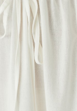 Tejido blanco ligero con un aspecto texturizado y tejido, y largas cintas. El material es transparente y cae suavemente.