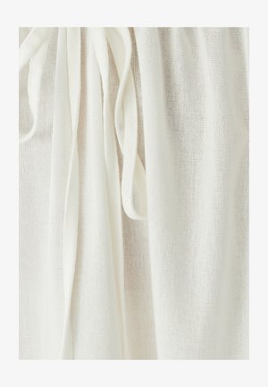 Tejido blanco ligero con un aspecto texturizado y tejido, y largas cintas. El material es transparente y cae suavemente.