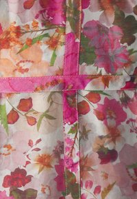Tela de vestido floral con un patrón de flores rosas, naranjas y verdes sobre un fondo claro, con detalles de costura en rosa.