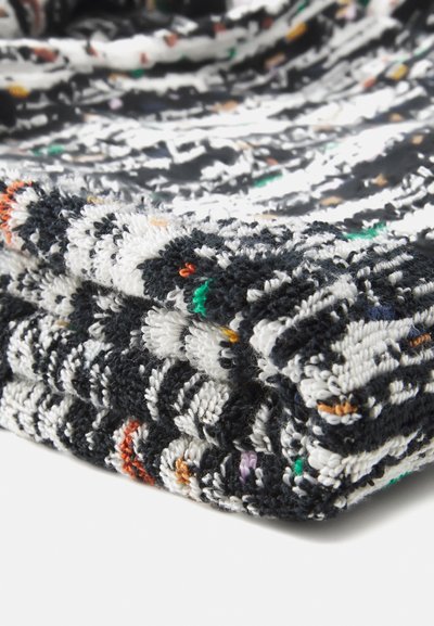 Tessuto intrecciato bianco e nero con una texture, arricchito da macchie colorate. Presenta una piega morbida e spessa, che mette in risalto un aspetto morbido e accogliente.