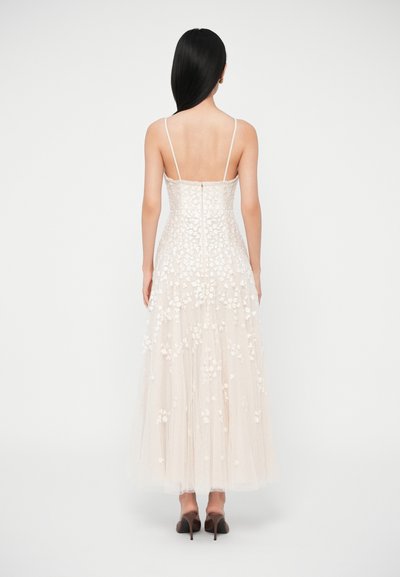 Μακρύ, ανοιχτόχρωμο φόρεμα με κεντήματα λουλουδιών, λεπτές τιράντες και στενή πλάτη. Υλικό τιλ με φαρδιά φούστα. Κλείσιμο με φερμουάρ στο πίσω μέρος.