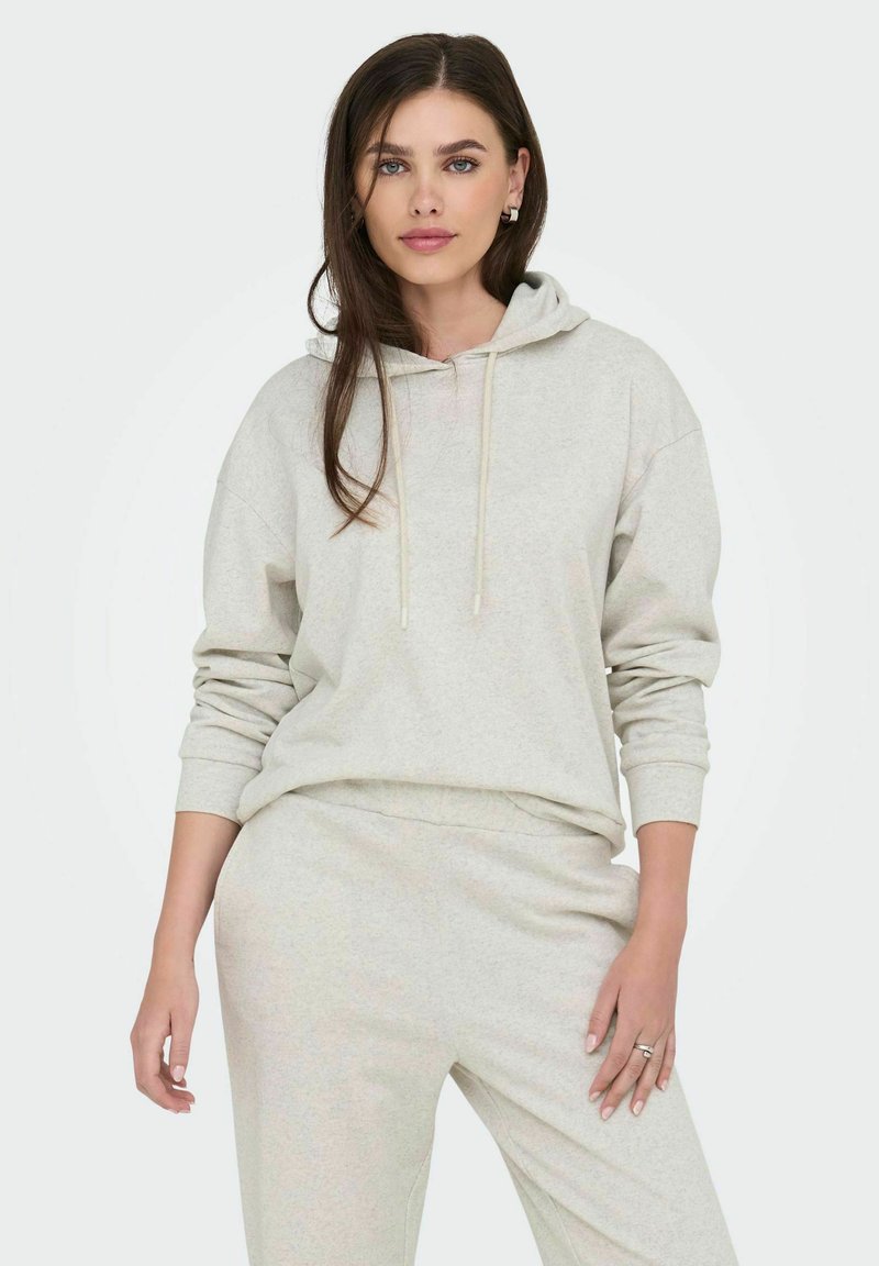 Hellgrauer Kapuzenpullover mit Kordelzügen und langen Ärmeln, kombiniert mit passenden hellgrauen Sweatpants, aus weichem Stoff und in lockerer Passform.