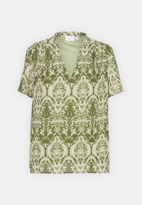 Blusa corta a maniche corte stampata verde con scollatura a V, caratterizzata da un motivo damascato floreale su uno sfondo chiaro. Tessuto leggero con una consistenza liscia.