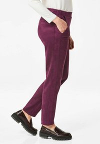 Paarse, gestructureerde broek met een rechte snit, voorzien van zijzakken en verticale naden, gecombineerd met donkere, robuuste instappers.