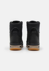 Schwarze High-Top-Sneaker mit einem strukturierten Obermaterial, Wildleder-Akzenten, einer Gummisohle und einer kontrastierenden braunen Außensohle. Die Rückansicht hebt den gepolsterten Kragen hervor.