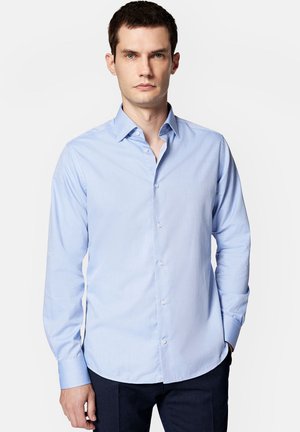 Jasnoniebieska koszula z długim rękawem z mieszanki bawełny, z kołnierzykiem zapinanym na guziki, z przodem na guziki i zaokrąglonym dołem. Gładka tekstura, dopasowany krój.