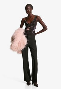 Črn top z ovitim ovratnikom in bisernim okrasjem, v kombinaciji z breznapennimi črnimi hlačami in roza umetnim krznom. Špicaste temne pete dopolnjujejo obleko.