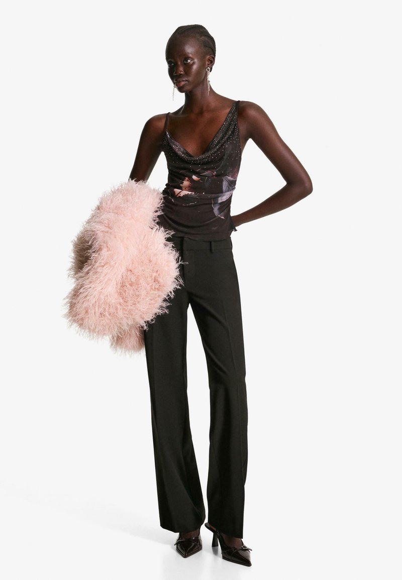 Črn top z ovitim ovratnikom in bisernim okrasjem, v kombinaciji z breznapennimi črnimi hlačami in roza umetnim krznom. Špicaste temne pete dopolnjujejo obleko.