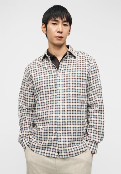 Chemise à boutons avec un motif à carreaux marron et bleu clair sur un fond beige, en tissu léger avec un col classique.