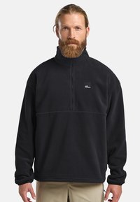 Pullover in fleece nero con colletto alto, zip a un quarto e un piccolo logo sul petto. Caratterizzato da maniche lunghe e una vestibilità ampia.